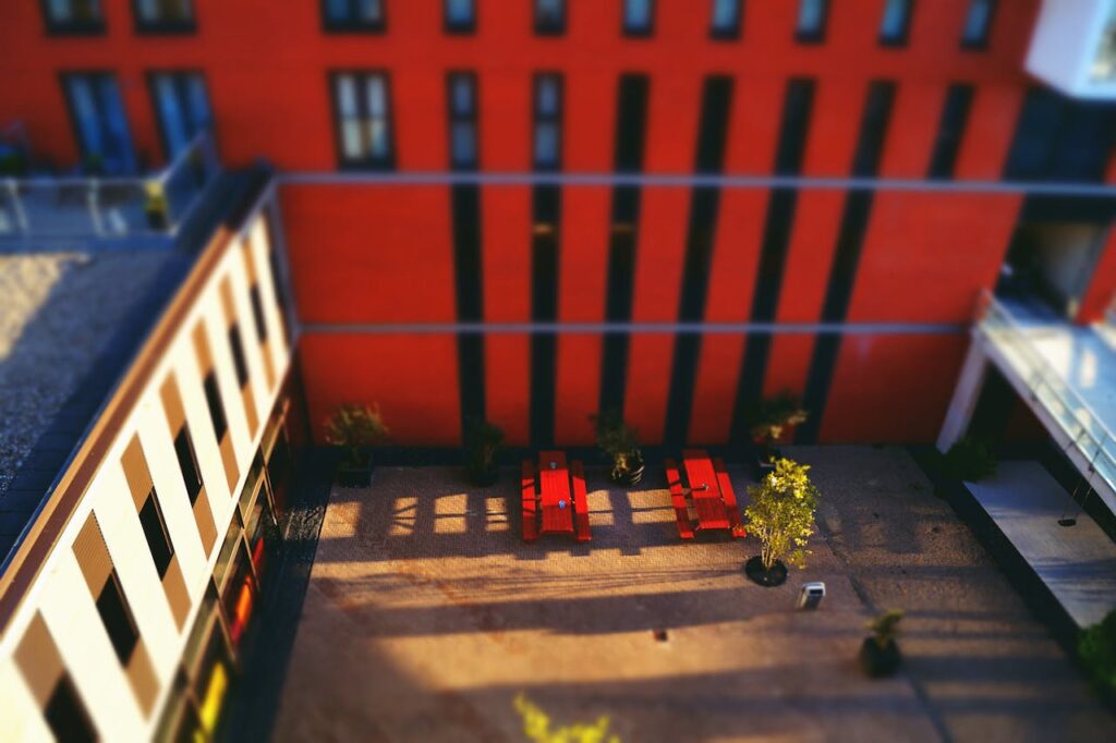 Aerial view of a contemporary urban courtyard with red benches and potted plants.