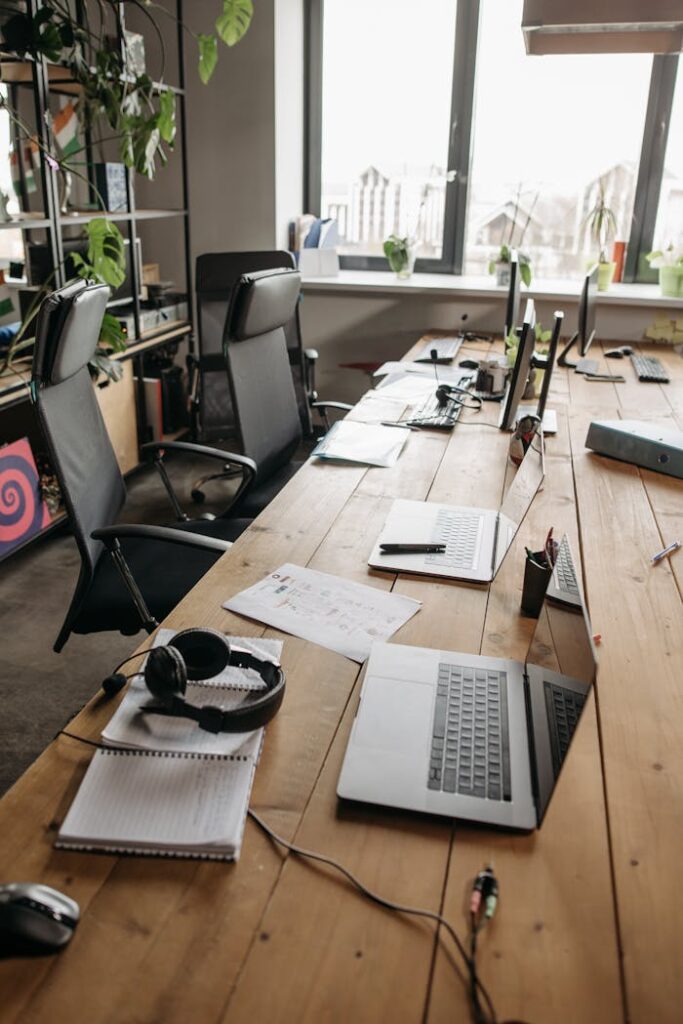 A contemporary office setting with laptops and chairs around a wooden table, ideal for teamwork.